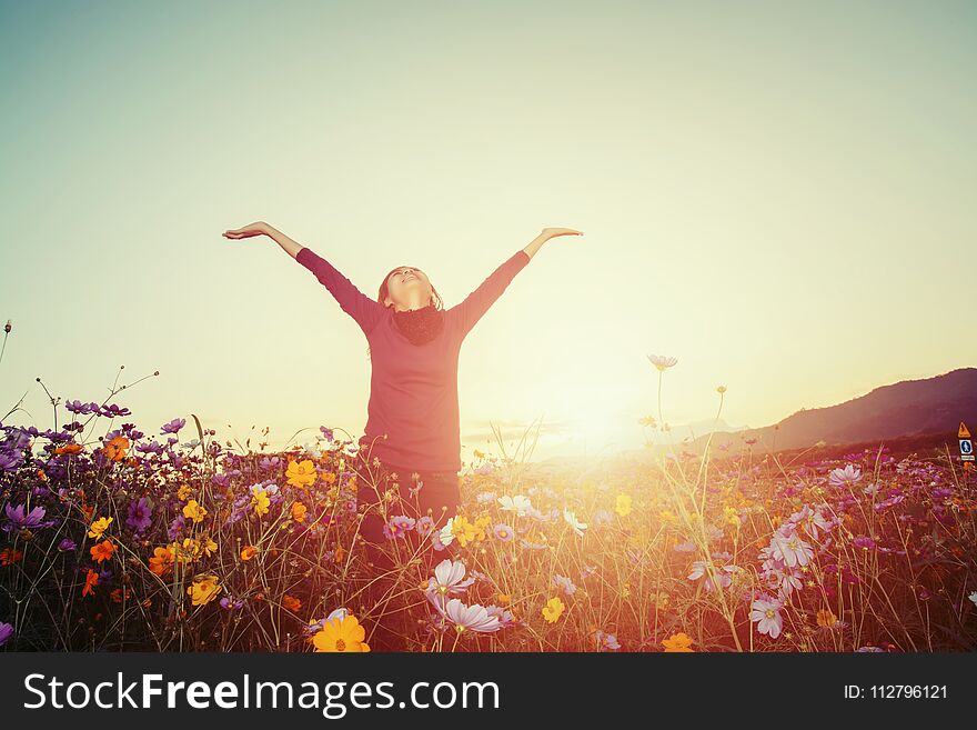 Lifestyle concept - beautiful happy woman enjoying fresh air in cosmos flower field