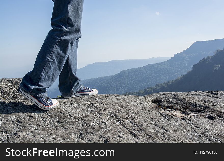 Man walking on edge of a cliff mountain top , travel concept On the Mountain