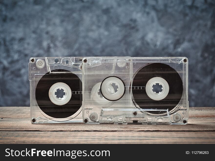 Audio cassettes close-up on a wooden shelf against a gray concrete wall. Retro technology for listening to music