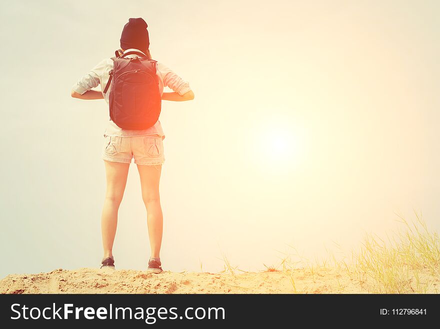 Woman with backpack standing on the beach, travel concetp background