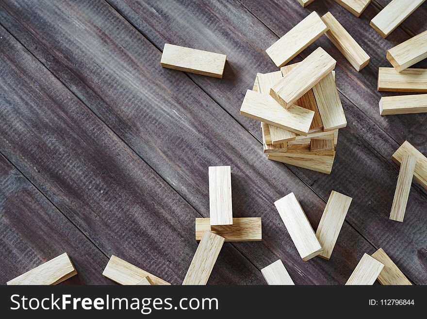 Crash of wooden building blocks tower on dark wood background with copy space. Collapse of wood blocks stack game background concept for business risk, imbalance, Collapse, destruction and Mistake