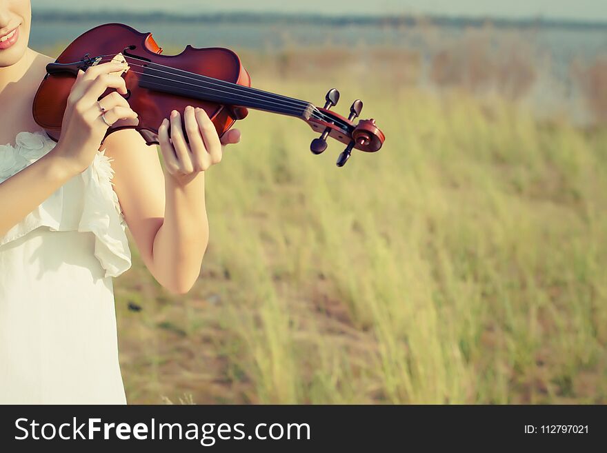 Beautiful Woman standing Playing the violin in the meadow background