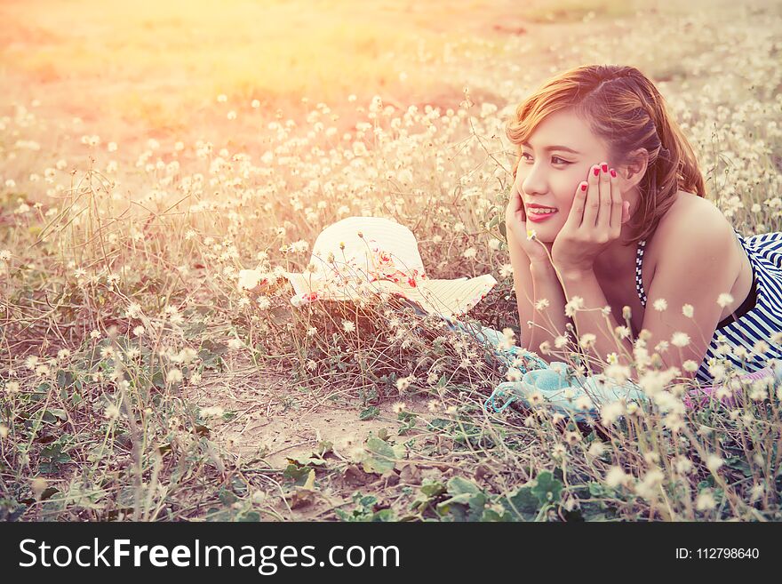 Young woman resting on the flower field and smile background