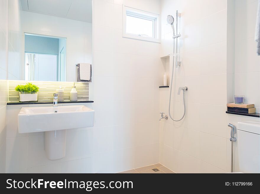 Tiwith a white ceramic basin and a mirror with a shower on a white wall. Tiwith a white ceramic basin and a mirror with a shower on a white wall.