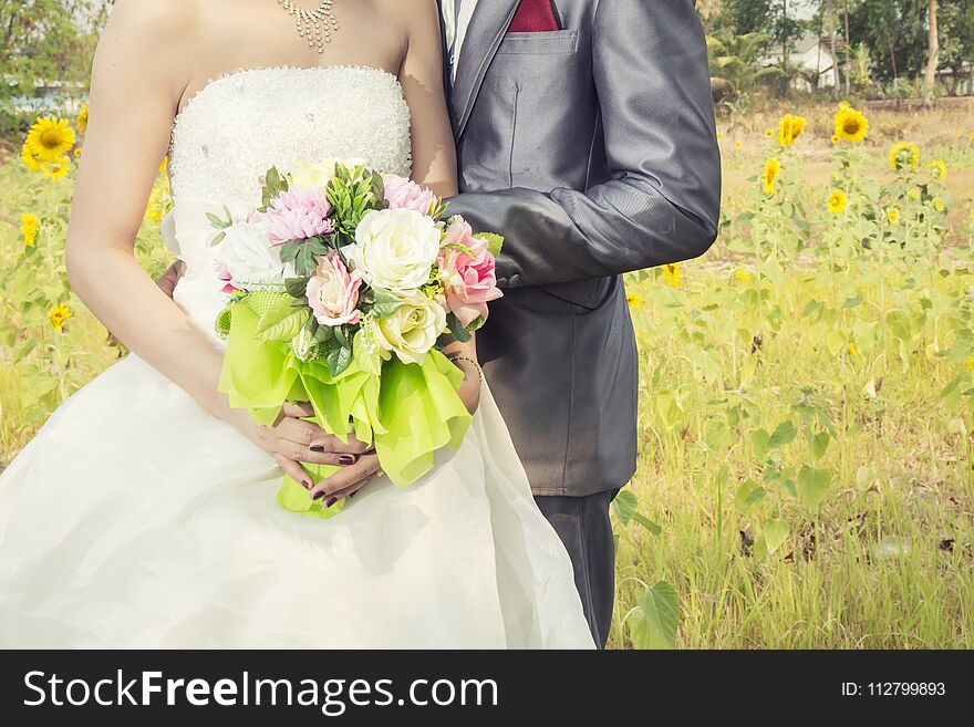 Beautiful bouquet of different colors in the hands of the bride in a white dress , wedding day