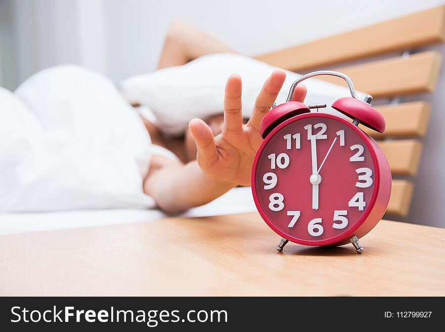 Young beautiful woman sleeping and alarm clock in bedroom at hom