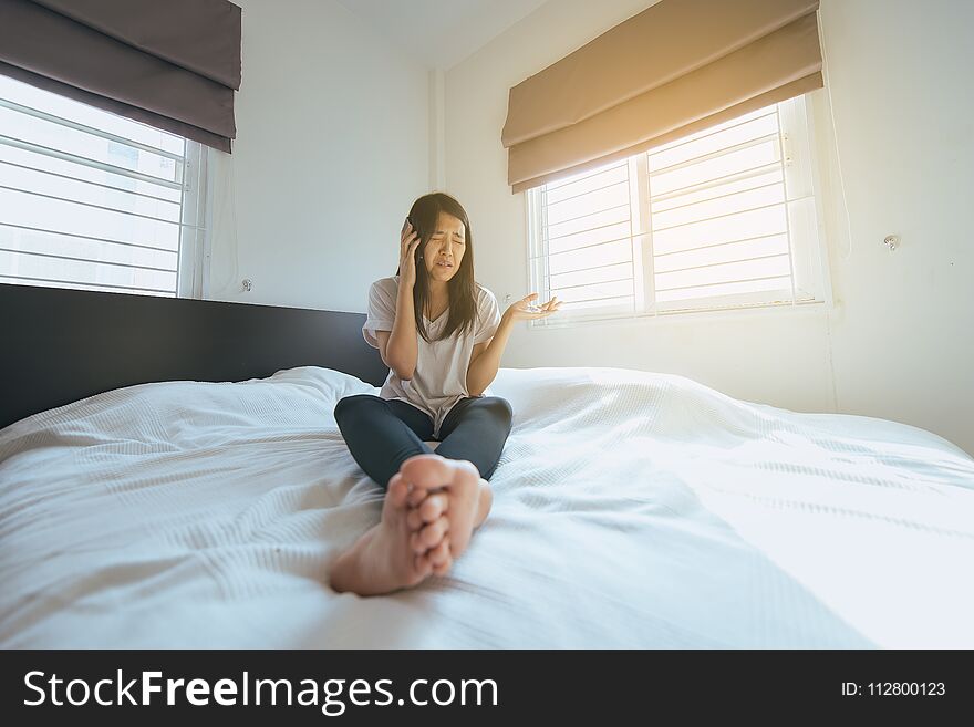 Asian woman talking with her mobilephone in bedroom at home feeling serious