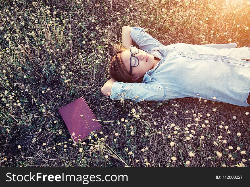 Beautiful young hipster laying down on the meadows field smiley