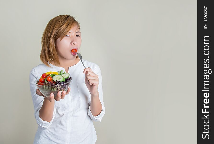 Beautiful Young Woman Using Fork To Eat A Tomato In Bowl Of Salad With Gusto.