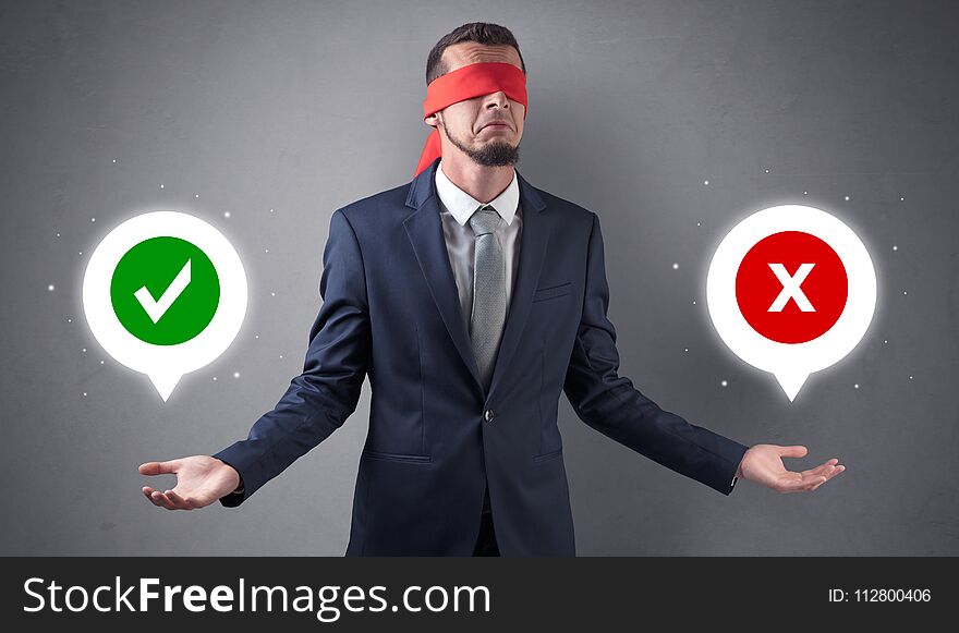 Blindfolded businessman with checked and x mark above his hand. Blindfolded businessman with checked and x mark above his hand