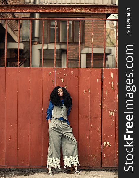 Woman Wearing Blue and Gray Outfit Standing Beside Gate