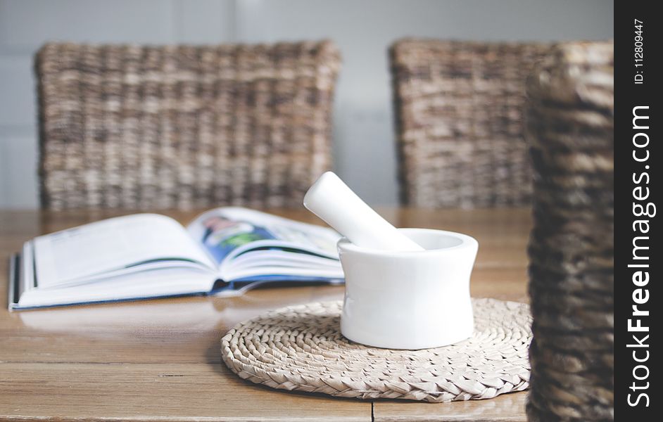 White Ceramic Mortar And Pestle Beside Book