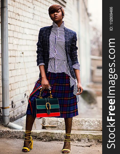 Woman in Blue and White Plaid Cardigan Holding Green and Red Handbag