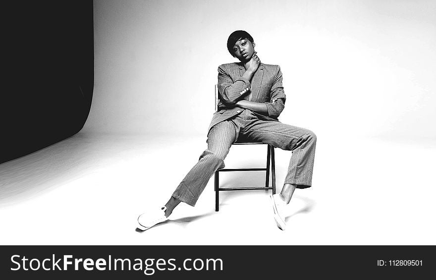 Grayscale Photo Of Person Sitting On Chair