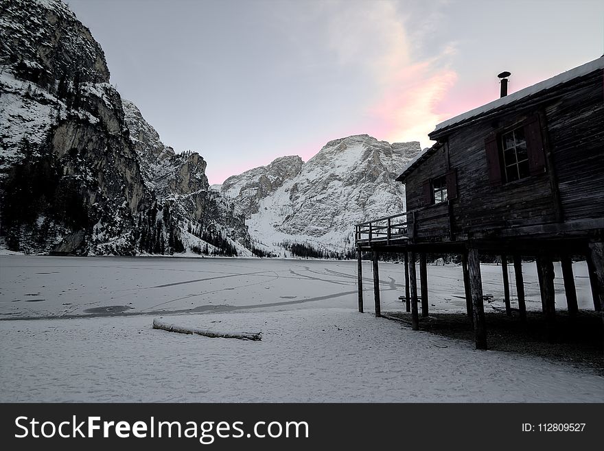 Wooden House Near Mountain Covered With Snow