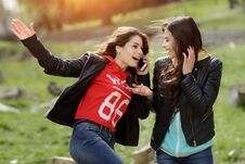 Two Pretty And Happy Young Woman Using The Mobile Phone In The Park. Best Friends. Stock Photos