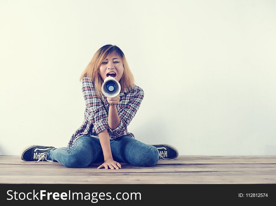 Young hipster woman shouting through megaphone background. Young hipster woman shouting through megaphone background
