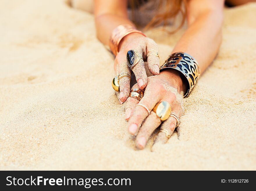 Woman`s hands with gold and expressive jewelry in sand. Woman`s hands with gold and expressive jewelry in sand