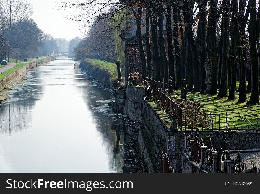 Water Canal In Spring Day, Sidewalk Along River Bank