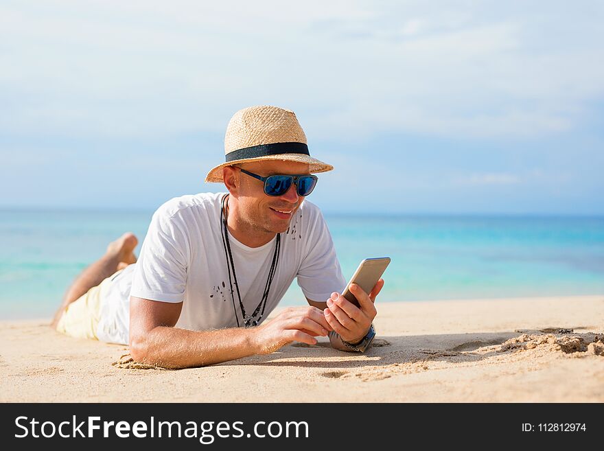 Handsome man with mobile phone on the tropical beach. Handsome man with mobile phone on the tropical beach