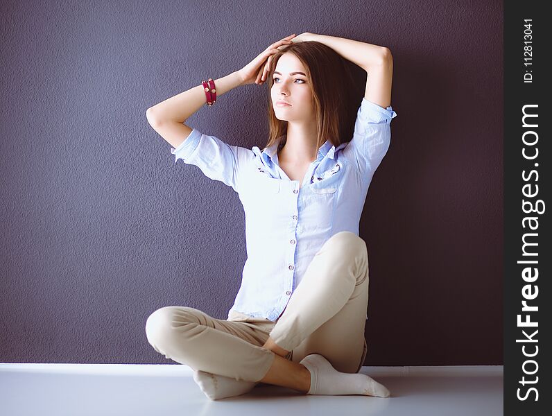 Young woman sitting on the floor near dark wall