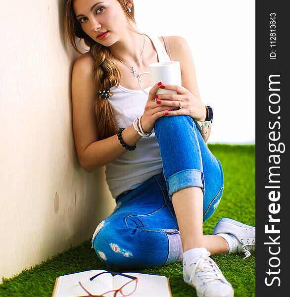 Young woman sitting with book on grass .