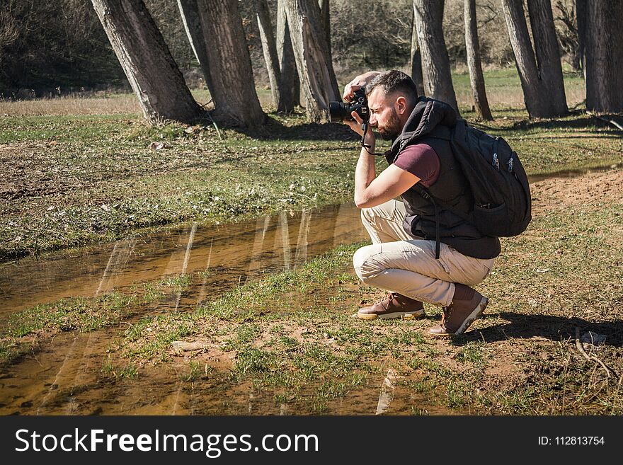 Photographer in nature takes pictures of the landscapes. Young berded man with camera.