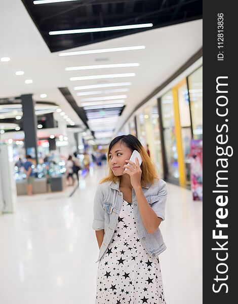 Young beautiful woman talks by a mobile phone in shopping mall background. Young beautiful woman talks by a mobile phone in shopping mall background