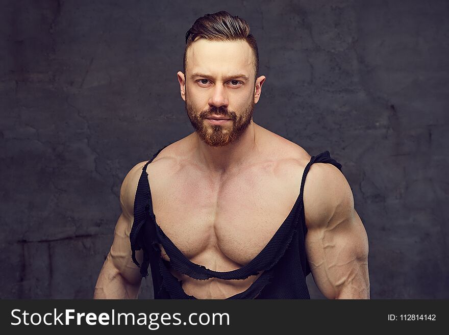 Shirtless bearded bodybuilder over grey background.