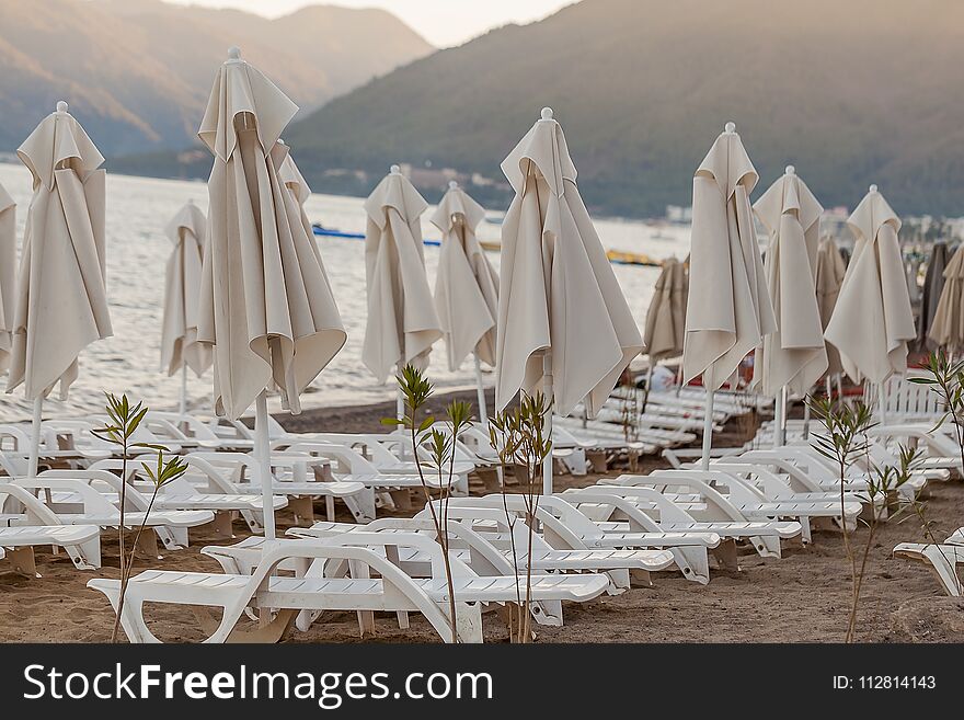 Beach umbrellas and sunbeds by the sea for vacationers in the evening. Beach umbrellas and sunbeds by the sea for vacationers in the evening.