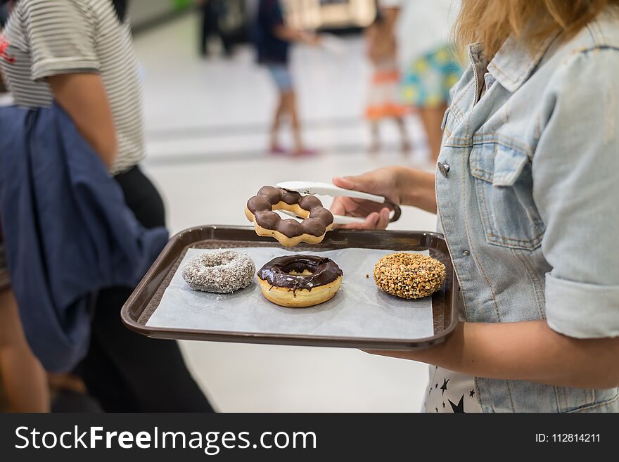 Young woman hand grabbing donut from tray to buying background. Young woman hand grabbing donut from tray to buying background