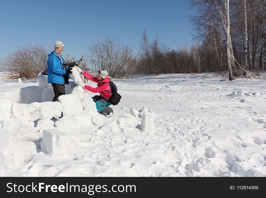 Man And Woman Building An Igloo On A Snow Glade