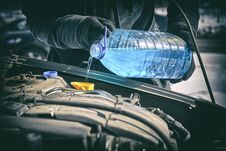 Man Pouring An Antifreeze Liquid In A Windshield Washer Tank Of A Car Stock Photos