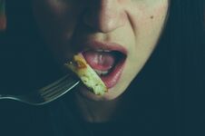 Part Of The Girls Face With Mouth And Tongue Holding Fork With Chicken Meat Eating In The Night, Hiding From Other People, Illumin Royalty Free Stock Image