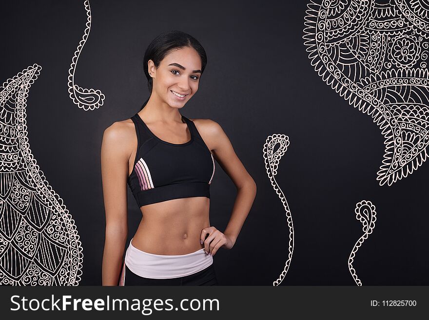 Keeping fit. Cheerful beautiful young woman in sports clothes smiling and feeling happy after having a productive training in the professional gym. Keeping fit. Cheerful beautiful young woman in sports clothes smiling and feeling happy after having a productive training in the professional gym