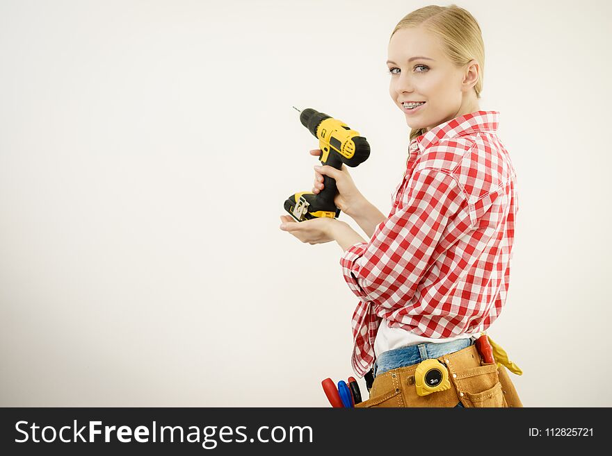 Young woman with toolbelt using driil and some power tools for her work at home. Girl working at flat remodeling. Building, repair and renovation. Young woman with toolbelt using driil and some power tools for her work at home. Girl working at flat remodeling. Building, repair and renovation.
