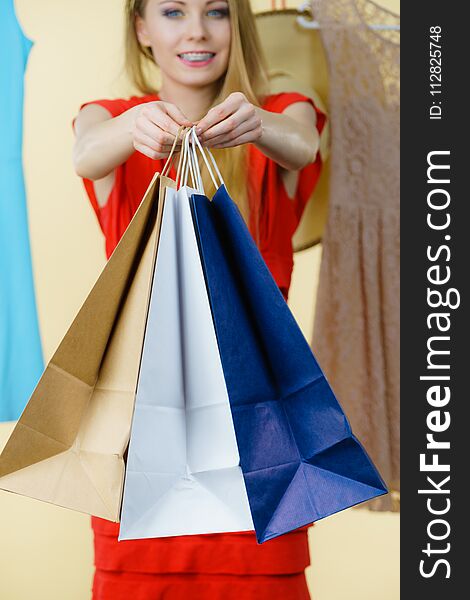 Woman in clothes shop store holding shopping bags picking summer perfect outfit, dress hanging on clothing hangers. Woman in clothes shop store holding shopping bags picking summer perfect outfit, dress hanging on clothing hangers