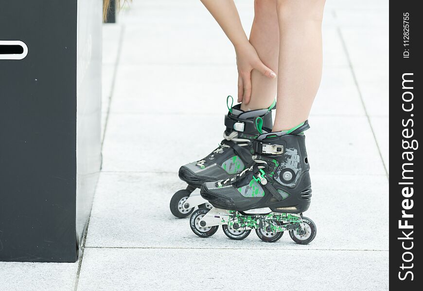 Woman slim legs wearing roller skates standing outside. Sport activity objects concept. Woman slim legs wearing roller skates standing outside. Sport activity objects concept.