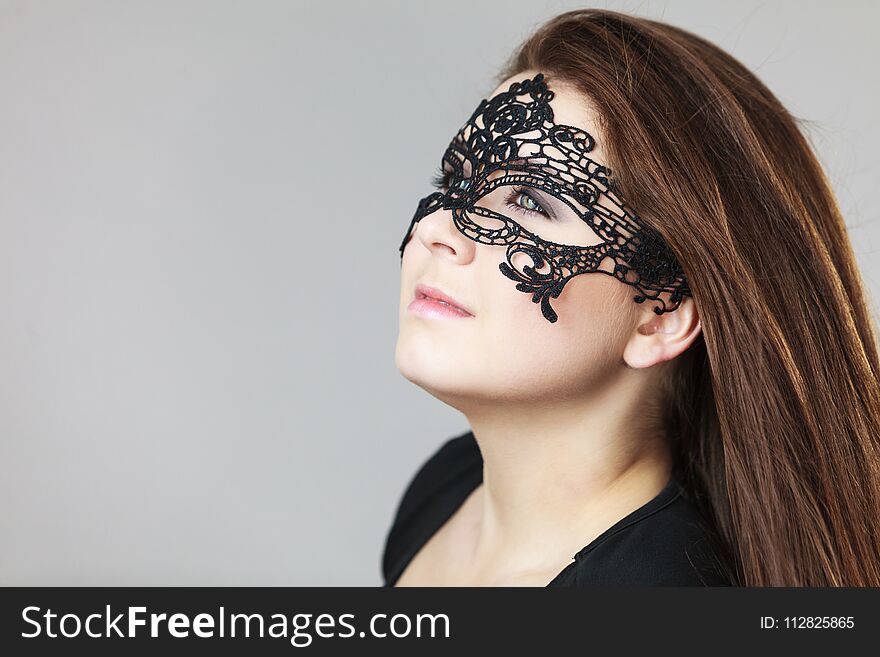 Pretty mysterious woman wearing black eye lace mask having tousled windblown long brown hair. Pretty mysterious woman wearing black eye lace mask having tousled windblown long brown hair.