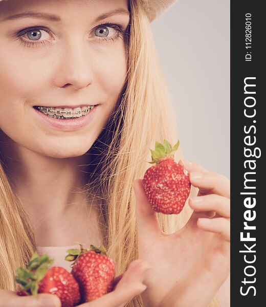 Young positive woman holding in hands fresh strawberries fruits on grey. Healthy meal. Toned image. Young positive woman holding in hands fresh strawberries fruits on grey. Healthy meal. Toned image