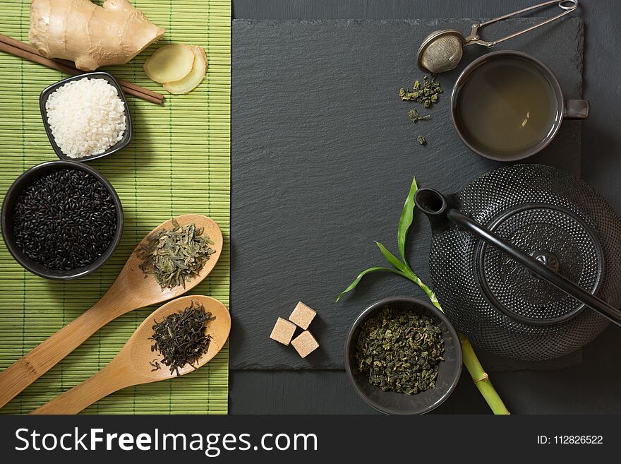 Green japanese and chinese tea with traditional food set on black stone table. Top view with copy space.