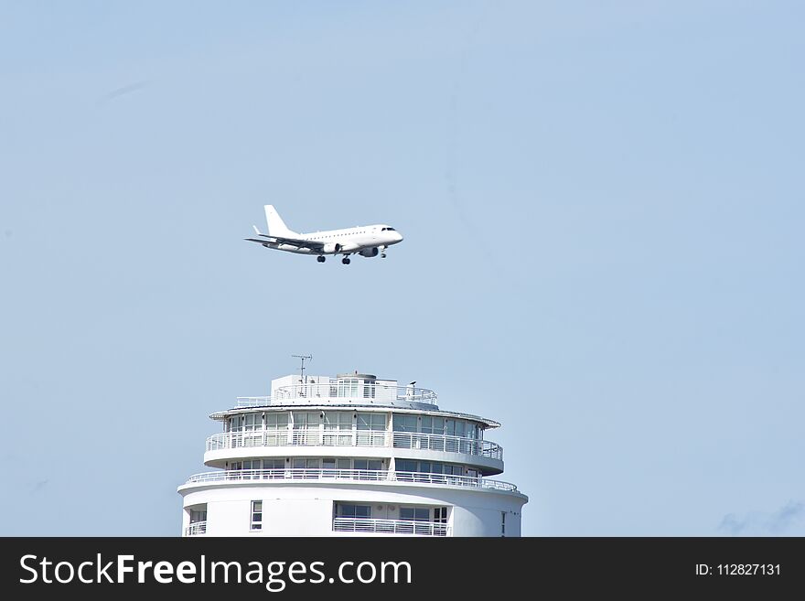 Plane coming in to land at London city airport as it flies over a tower building. Plane coming in to land at London city airport as it flies over a tower building