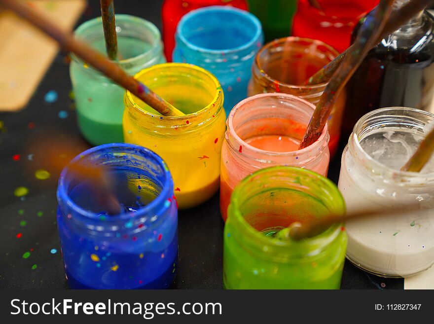 Different glass containers with different colors for painting and brushes