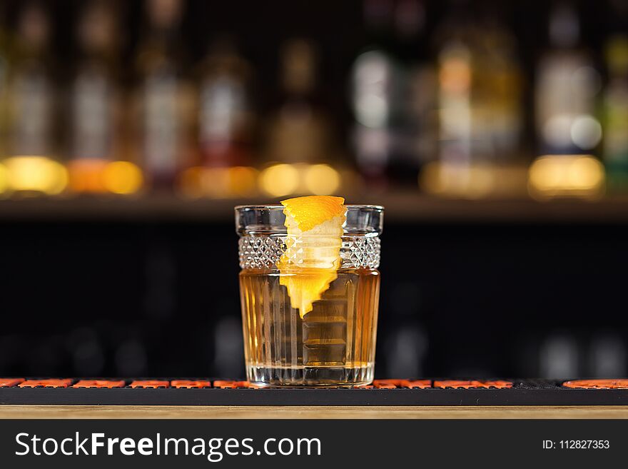 Glass of whiskey cognac or brandy with lemon and ice cubes standing on the bar counter