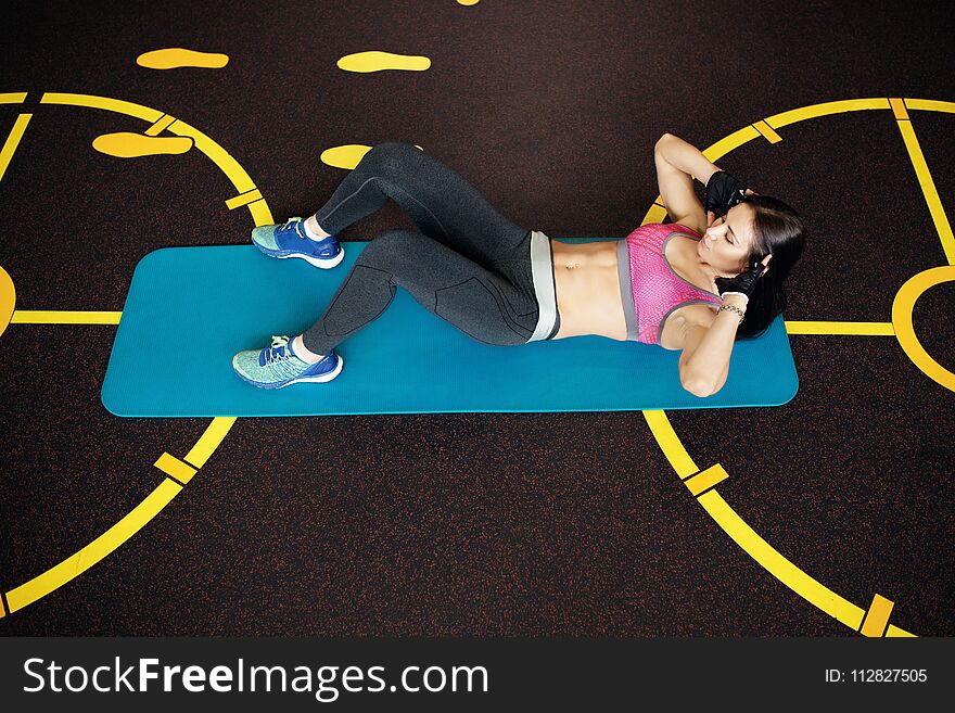 Athletic young woman exercises abs ont he fitness mat.