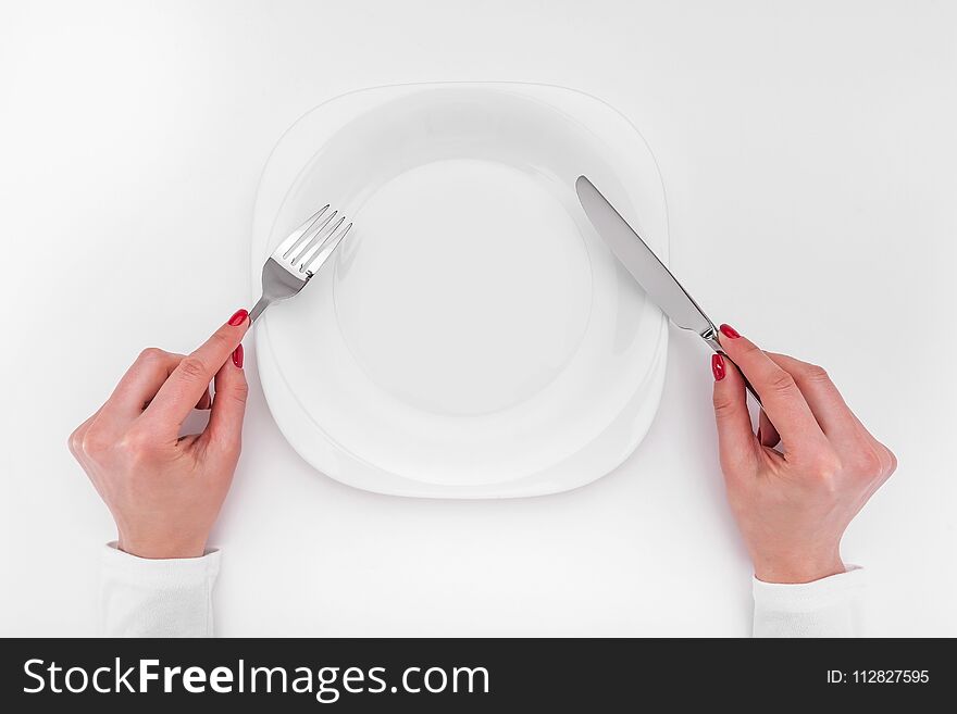 Hands with cutlery over empty plate. A place to place your image.