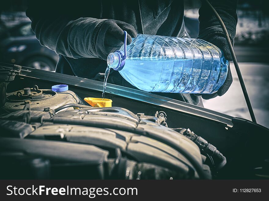 Man Pouring An Antifreeze Liquid In A Windshield Washer Tank Of A Car