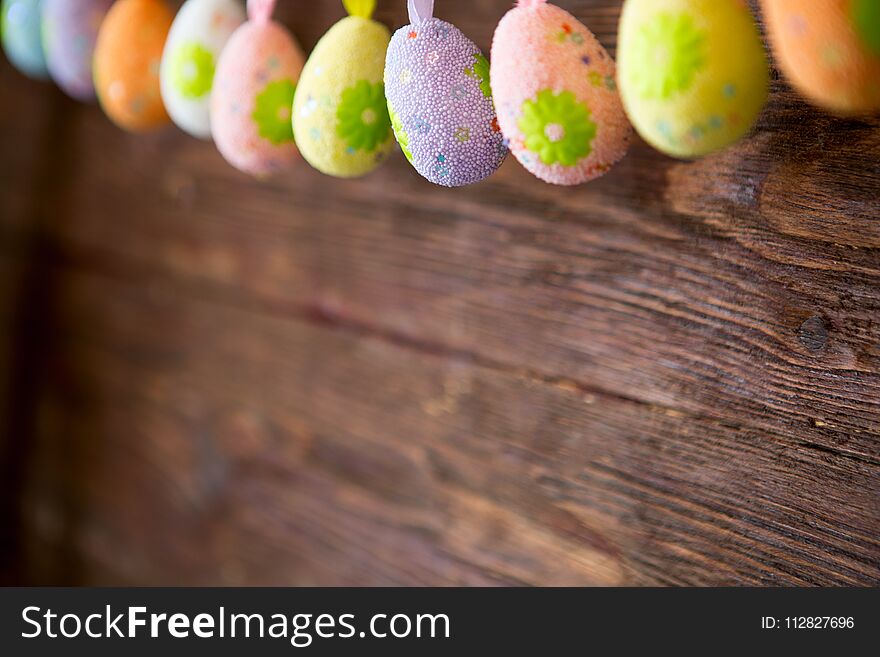 Handmade easter garland with painted eggs on wooden background. Colorful easter holiday decoration on rustic wall.