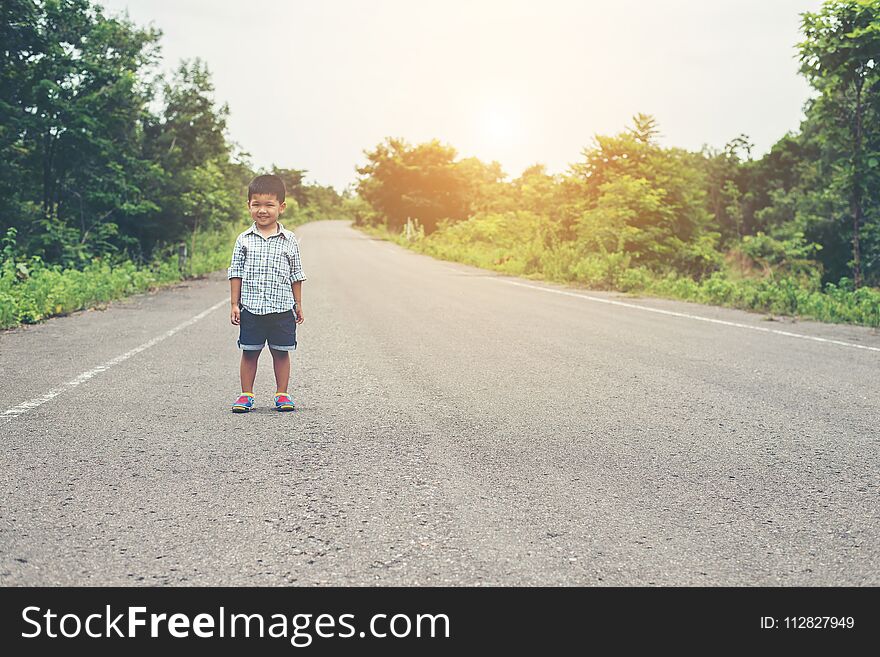 The boy stood on the street and smiling at the camera with a fresh mind.