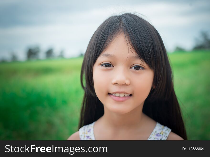 Close up of sweet little girl outdoors with smiling in the summer field.